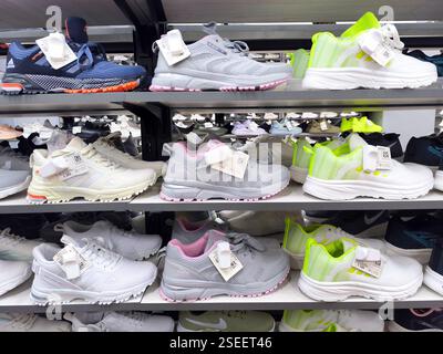Verschiedene sportliche Sneakers in den Regalen des Stores. Stockfoto