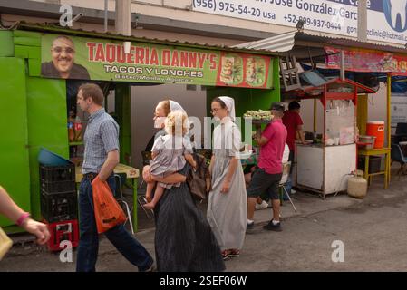 Mann mit zwei Frauen in religiöser Kleidung, möglicherweise Mormon, eine mit einem Baby, der die Straße der Grenzstadt Nuevo Progreso, Mexiko, entlang läuft. Stockfoto