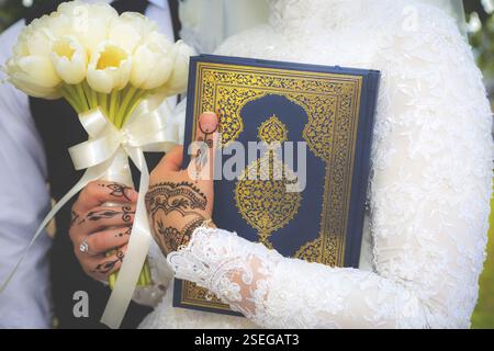 Islamische Hochzeitszeremonie muslimische Braut hält einen koran und einen Blumenstrauß aus nächster Nähe Stockfoto