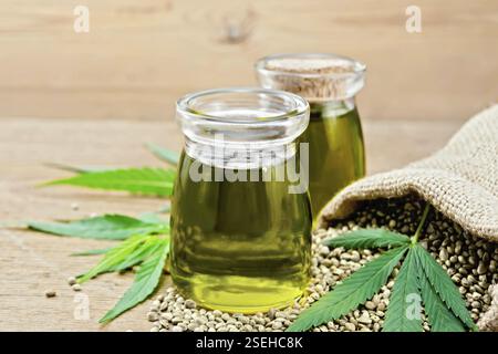 Hanf Öl in zwei Gläsern, Korn in der Tasche und auf dem Tisch, Cannabis Blätter auf dem Hintergrund der alten Platine Stockfoto