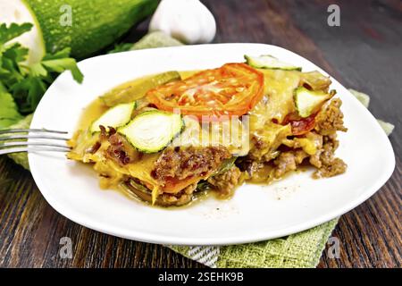 Aus Hackfleisch, Tomaten und Zucchini in einer Platte auf eine Serviette, Gabel Kasserolle, auf einem Holzbrett Hintergrund Knoblauch Stockfoto