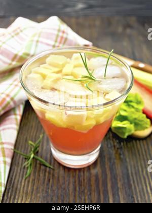Limonade mit Rhabarber und Rosmarin in einem Glas, Stiele und ein Blatt eines pflanzlichen, Serviette auf einem Hintergrund von dunklem Holz board Stockfoto