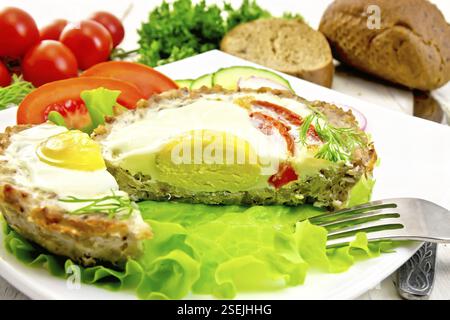 Törtchen mit Fleisch mit Ei und Tomate schnitt in die Platte auf Salat, Brot und Dill auf dem Hintergrund Licht Holzbretter Stockfoto