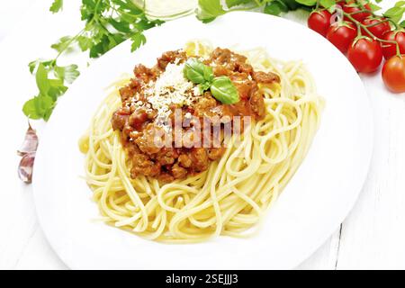 Spaghetti-Pasta mit Bolognese-Sauce aus Hackfleisch, Tomatensaft, Knoblauch, Wein und Gewürze mit Käse in einem Teller, Pflanzenöl, würziges Kraut auf einem Whit Stockfoto