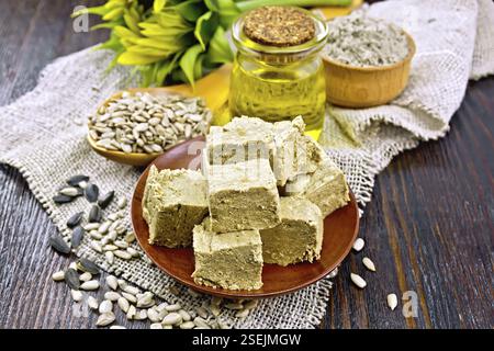 Östlichen süße halva Sonnenblumen in einer Platte, Sonnenblumenkerne, Öl, Mehl und Blume auf der Leinwand auf dem Hintergrund einer Holzplatte Stockfoto