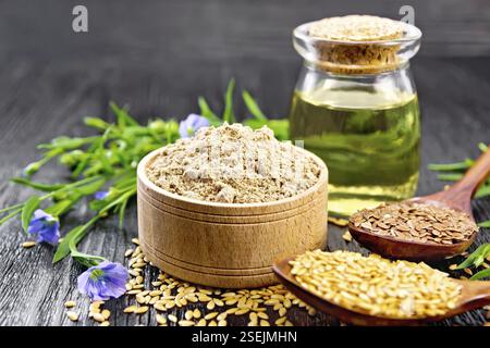 Leinsamen Mehl in eine Schüssel, weißen und braunen Samen in Löffel und am Tisch, Flachs, Blätter und Blüten, Öl in einem Glas auf dunklen Holzplatte Hintergrund Stockfoto