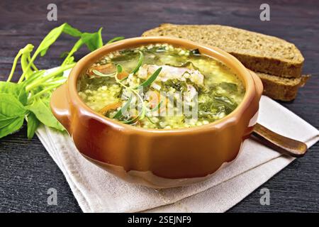 Schweinerippchen Suppe mit Couscous und Spinat in einer Schüssel auf Serviette, Brot auf Holzbrett Hintergrund Stockfoto