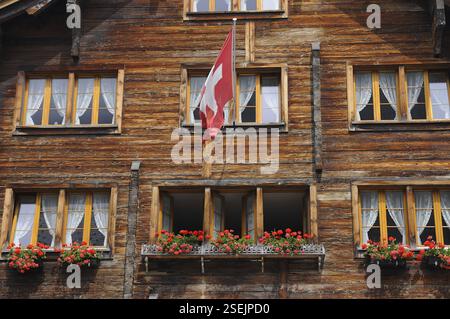 Traditionelles schweizer Holzhaus mit Flagge in den Alpen, der Schweiz, Europa Stockfoto