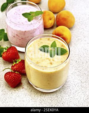 Zwei Gläser Milchcocktail mit Aprikosen, Erdbeeren und Minze auf dem Steintisch Stockfoto