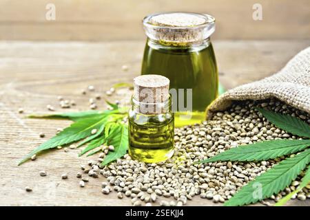 Hanf Öl in zwei Gläser mit Getreide im Sack, Blätter und Stängel von Cannabis auf dem Hintergrund der alten hölzernen Brettern Stockfoto