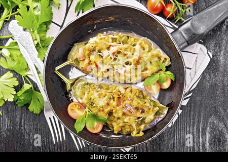 Gefüllte Aubergine mit geräuchertem Brisket, Tomaten, Zwiebeln, Karotten mit Knoblauch, Käse und Kräutern in einer Pfanne auf Serviette auf Holzbrett Hintergrund von abo Stockfoto