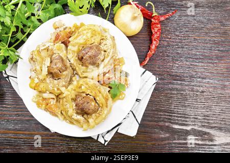 In der Mitte verdrehte Pasta mit Fleischbällchen mit Sahnesauce, geschmorten Tomaten, Paprika, Zwiebeln und Knoblauch auf weißem Teller auf Holzbrett-Backgroun Stockfoto