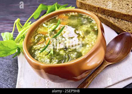 Schweinerippchen Suppe mit Couscous und Spinat in einer Schüssel auf dem Handtuch, Brot auf Holzbrett Hintergrund Stockfoto