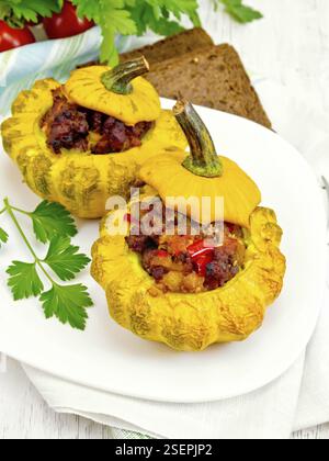 Zwei gelbe Zucchini gefüllt mit Fleisch, Tomaten und Paprika in die Schüssel, Brot, Petersilie und eine Serviette auf dem Hintergrund Licht Holzbretter Stockfoto