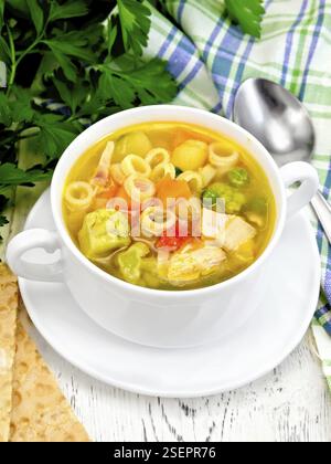 Minestrone mit Fleisch, Sellerie, Tomaten, Zucchini, Kohl, Erbsen, Möhren und Nudeln in eine Schüssel, Handtuch, Brot auf einem hölzernen Brettern Hintergrund Stockfoto