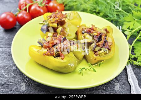 Paprika gefüllt mit Pilzen, Tomaten, Zucchini, Auberginen und Zwiebeln, mit Wein, Knoblauch, Thymian und Gewürze in einem grünen Platte gegen Bl gewürzt Stockfoto