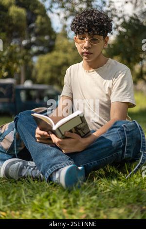 Eine Person, die ein Buch liest, während sie an einer Bushaltestelle auf den Bus wartet. Perfekt für Themen wie Lesen, Reisen, Warten und alltägliche Momente. Stockfoto