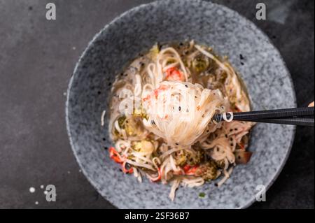 Asiatische Glasnudeln mit Krabbenfleisch und Gemüse in einer Schüssel. Schwarzer Hintergrund. Draufsicht. Stockfoto