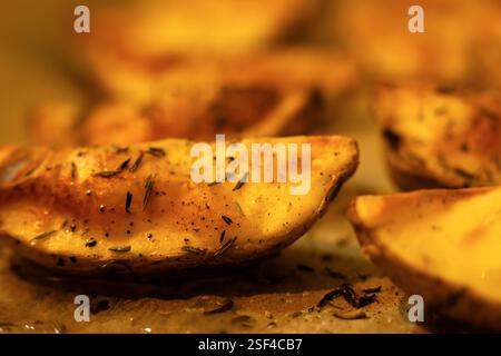 Gebackene Kartoffeln mit Thymian und schwarzem Pfeffer in Nahaufnahme. Kartoffelkeile mit Arten. Stockfoto