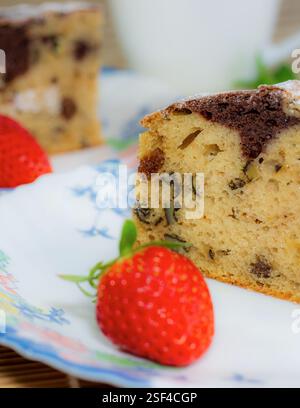 Marmorkuchen mit Rosinen und Walnüssen. Ein Stück Kuchen auf einem Teller mit einer Erdbeere. Stockfoto