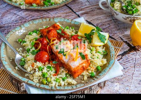 Harissa-Lachs mit Bulgur-Weizen, Kirschtomaten und grünen Erbsen Stockfoto