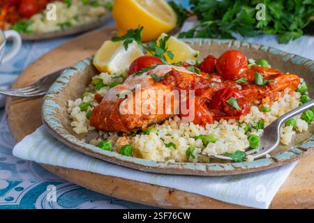 Harissa-Lachs mit Bulgur-Weizen, Kirschtomaten und grünen Erbsen Stockfoto