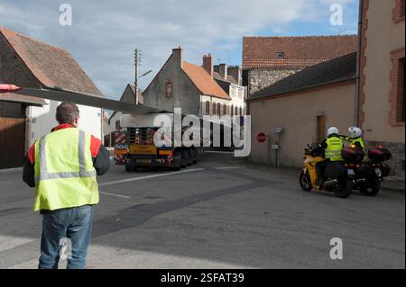 Ein außergewöhnlicher Konvoi, der eine Windkraftanlage transportiert, manövriert, um die Richtung zu ändern. Ein Assistent steuert die Ausrichtung der Räder des Anhängers. Stockfoto