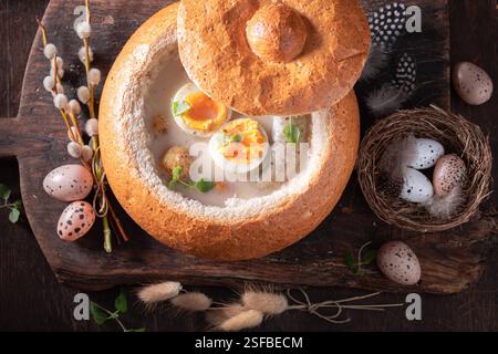 Heiße Sauersuppe mit Eiern, Kartoffeln und Würstchen. Sauergerstensuppe zu Ostern. Stockfoto