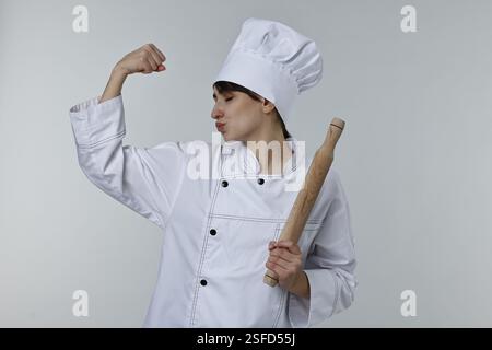 Professioneller Koch mit Pin-Küssen Bizeps auf hellgrauem Hintergrund Stockfoto