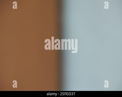 Grau-brauner, verschwommener Hintergrund, geteilt durch einen Schattenstreifen in zwei gleiche Teile, abstraktes einfaches zweifarbiges Bokeh mit verschwommener Textur und leerem Kopierraum Stockfoto