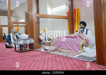 Bei einem Morgengottesdienst liest ein Sikh-Priester die ganze Bibel, während die Anbeter aufmerksam zuhören. In einem Tempel in Queens, New York. Stockfoto