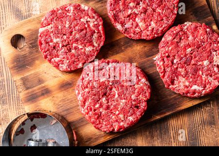 Hausgemachte, rohes Rindfleisch-Burger-Patties auf einem Holzbrett. Hamburger Zubereitung. Blick von oben. Hochwertige Fotos. Stockfoto