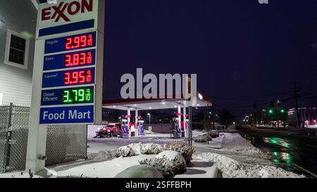 NORWALK, CT, USA - 9. FEBRUAR 2025: Die in Schnee gehüllte Exxon-Tankstelle zeigt die Kraftstoffpreise an, wenn die Nacht auf einer ruhigen Straße im Winter einbricht. Stockfoto