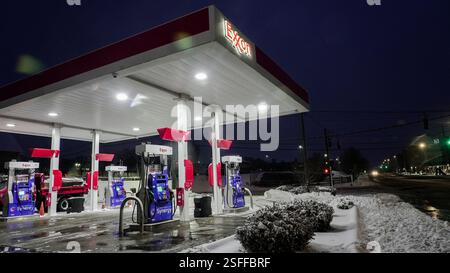 NORWALK, CT, USA - 9. FEBRUAR 2025: Schnee bedeckt den Boden, während eine Tankstelle nachts hell beleuchtet bleibt und Reisende und Einheimische in der Gegend bedient. Stockfoto