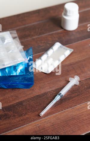 Nahaufnahme eines Holztisches mit Spritze, einer Blisterpackung mit Pillen und einer Flasche. Die Spritze befindet sich neben der Blisterpackung, die mit der Stockfoto