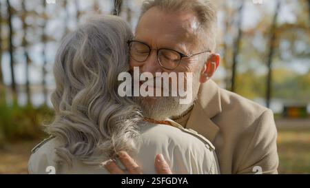 Reifes Paar umarmt im Herbstpark Senioren grauhaarige 60er Jahre Mann umarmt Frau glücklich verheiratete Familie umarmt Umarmen Liebe Unterstützung Pflege Romantik im Alter Stockfoto