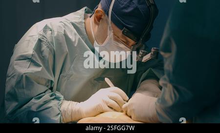 Zwei Ärzte operieren Patient in der Klinik Krankenhaus Chirurg Mann Arzt führen chirurgische Operation Kaiserschnitt Bauch plastische Chirurgie Schnitt Stockfoto