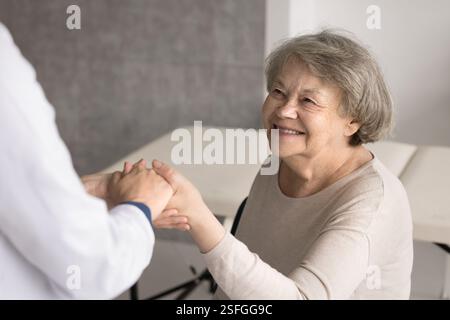 Glückliche ältere Großmutter-Patientin gibt dem vertrauten Arzt die Hand Stockfoto