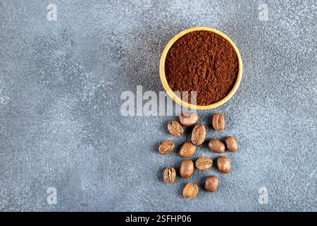 Kaffeebohnen mit einer Schüssel gemahlenen Kaffees auf grauem Hintergrund Stockfoto