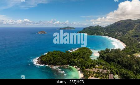 Tropische Insel mit üppigem Grün, umgeben von lebhaftem türkisfarbenem Wasser unter klarem Himmel. Seychellen, Mahe. Stockfoto