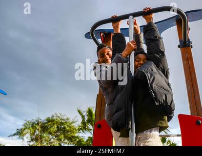 Zwei Brüder hängen auf einem Spielplatz und genießen einen sonnigen Tag im Park Stockfoto