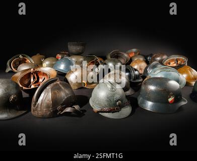 Sammlung historischer Militärhelme aus verschiedenen Epochen als Relikte vergangener Kriege und militärischer Traditionen auf schwarzem Hintergrund mit dramatischer Terra Stockfoto