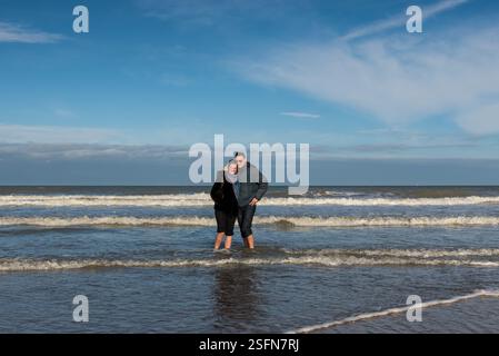 Paare posieren mit den Füßen im Meer, Ostende, Flandern, Belgien. Modell freigegeben Stockfoto