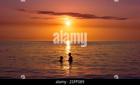 Silhouette von zwei Personen, die vor einem Sonnenuntergang im indischen Ozean schwimmen, Mauritius Island Stockfoto