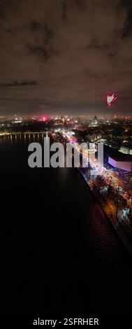 Die atemberaubende Aussicht bei Nacht zeigt eine lebhafte Stadtlandschaft, die sich wunderbar auf dem ruhigen Wasser unter ihr spiegelt Hannover Maschsee Neujahr 2025 FPV Stockfoto