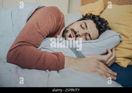 Junger gutaussehender Mann aus dem Nahen Osten, der friedlich in seinem Bett schläft. Stockfoto
