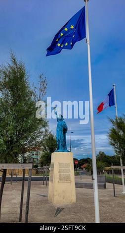 Die Freiheitsstatue, die Freiheit, die die Welt erleuchtet, in der Nähe der französischen Flagge und der Flagge der Europäischen Union. 30. Juni 2023. Soulac-sur-Mer, Nouvelle-Aquitaine Stockfoto