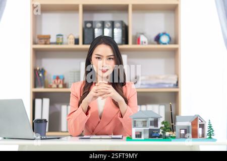Asiatische Immobilienmaklerin sitzt im Büro und bereitet Dokumente vor. Geschäftsfrau Immobilienmakler, weil Immobiliengeschäft weiter wird Stockfoto