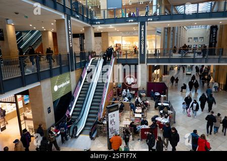 Grand Arcade Cambridge ist ein pulsierendes Einkaufszentrum mit Menschen, die in Geschäften stöbern und auf Rolltreppen fahren, in einem modernen Ambiente Stockfoto