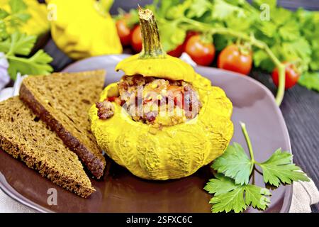 Squash gelb gefüllt mit Fleisch, Tomaten und Paprika, Brot in der Platte, Tomaten, Petersilie auf einem dunklen Holz- Board Stockfoto